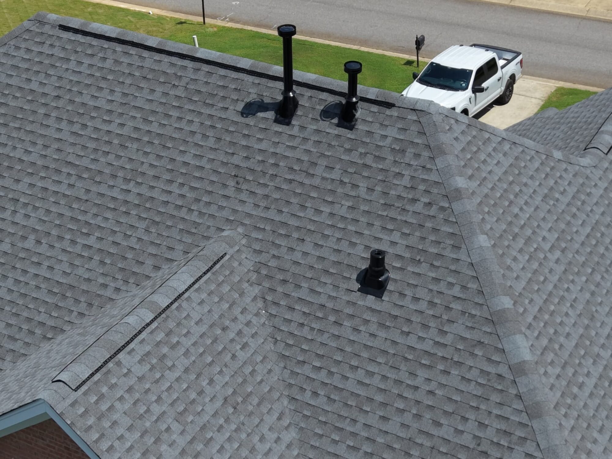 Finished gray architectural shingle roof with new black vent boots and ridge vent