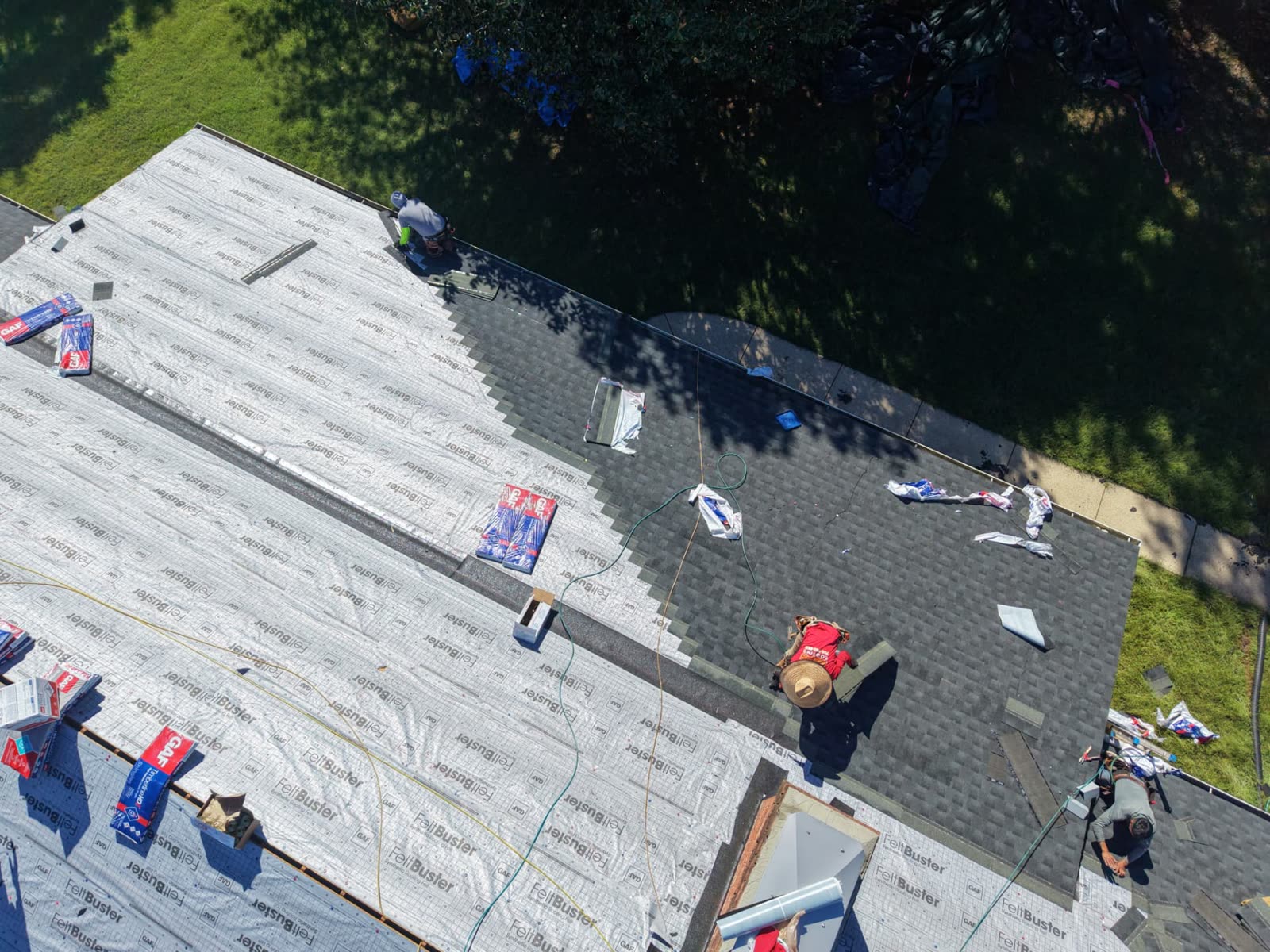 Aerial view of a crew installing charcoal architectural shingles over new GAF synthetic underlayment on a residential roof