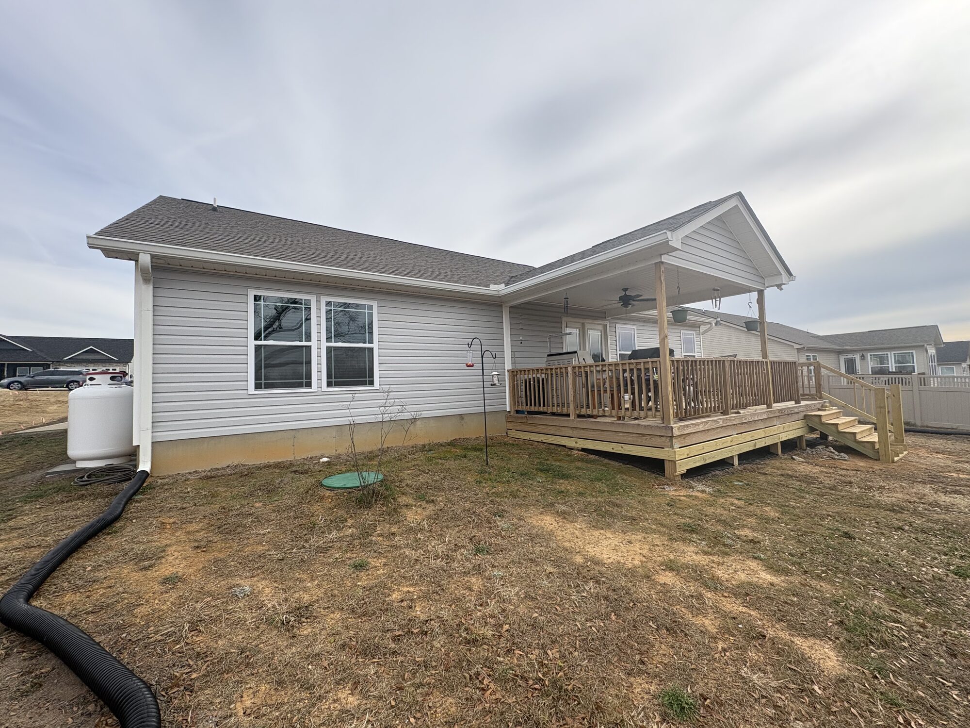 Newly built home with light gray siding and new white seamless gutters and downspouts
