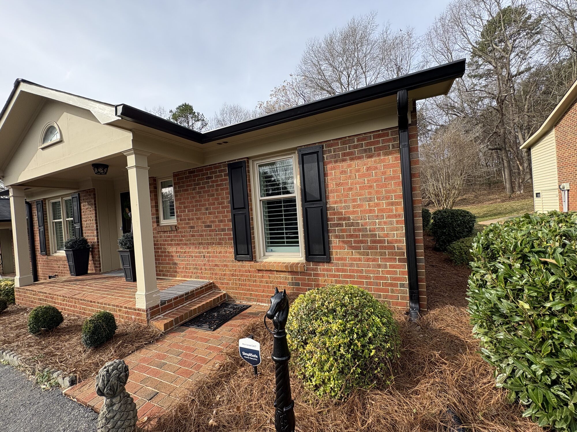 Brick ranch home with new dark bronze seamless gutters and downspouts along the roofline