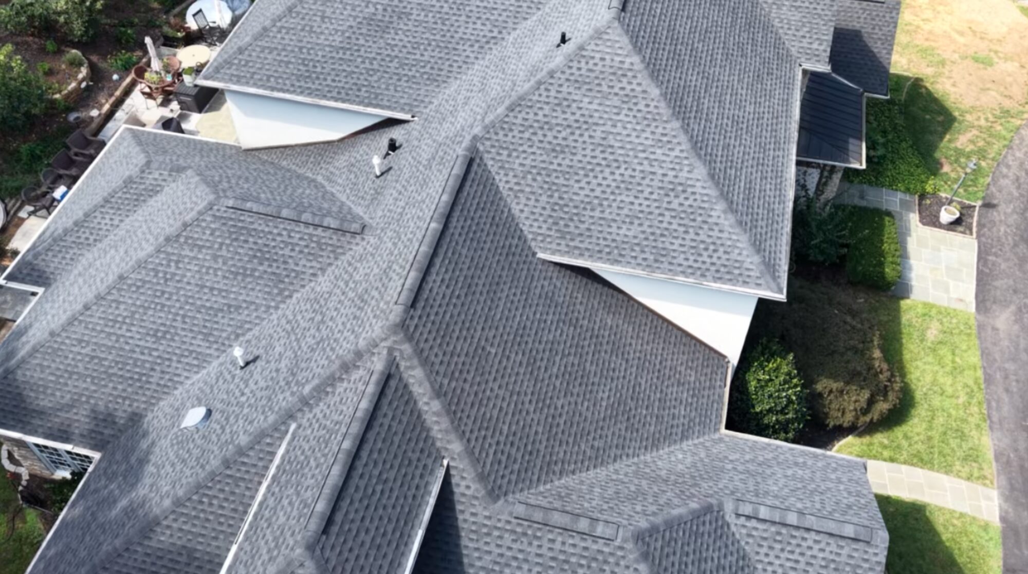 Aerial view of a finished gray architectural shingle roof with many hips and valleys on a large home